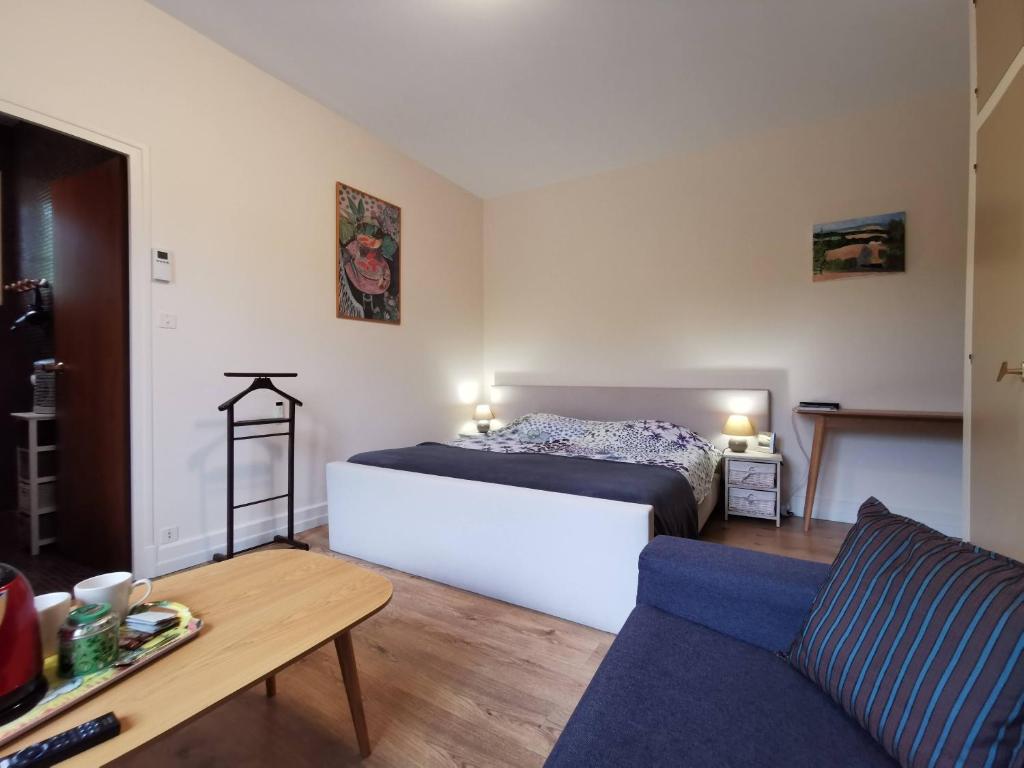 1 dormitorio con cama, sofá y mesa en Belle chambre d'hôtes avec petit déjeuner chez Phil et Isa, en Nérac