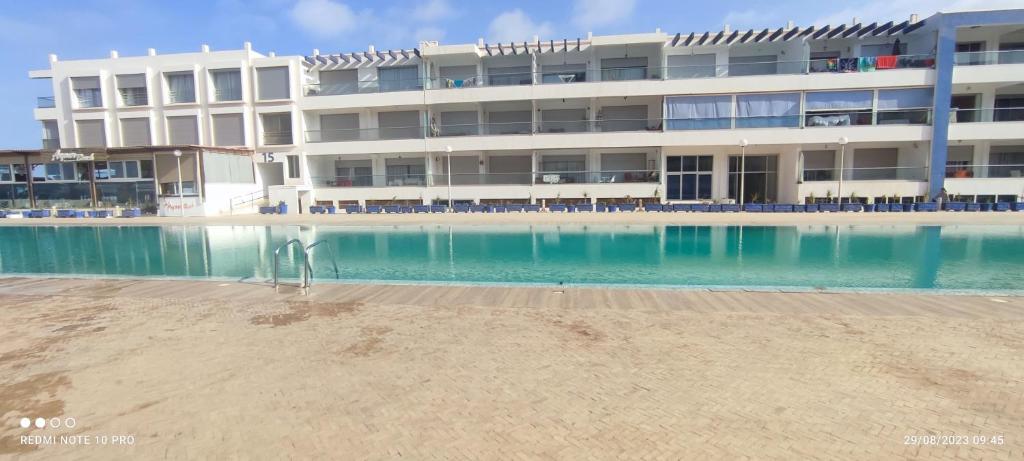 a hotel with a swimming pool in front of a building at Adan beach in Aourir