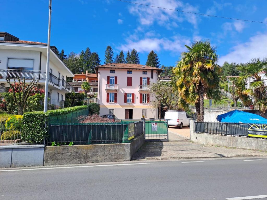 eine Stadtstraße mit einem rosa Haus und Palmen in der Unterkunft VILLA AIDA LAKE VIEW in Lavena Ponte Tresa