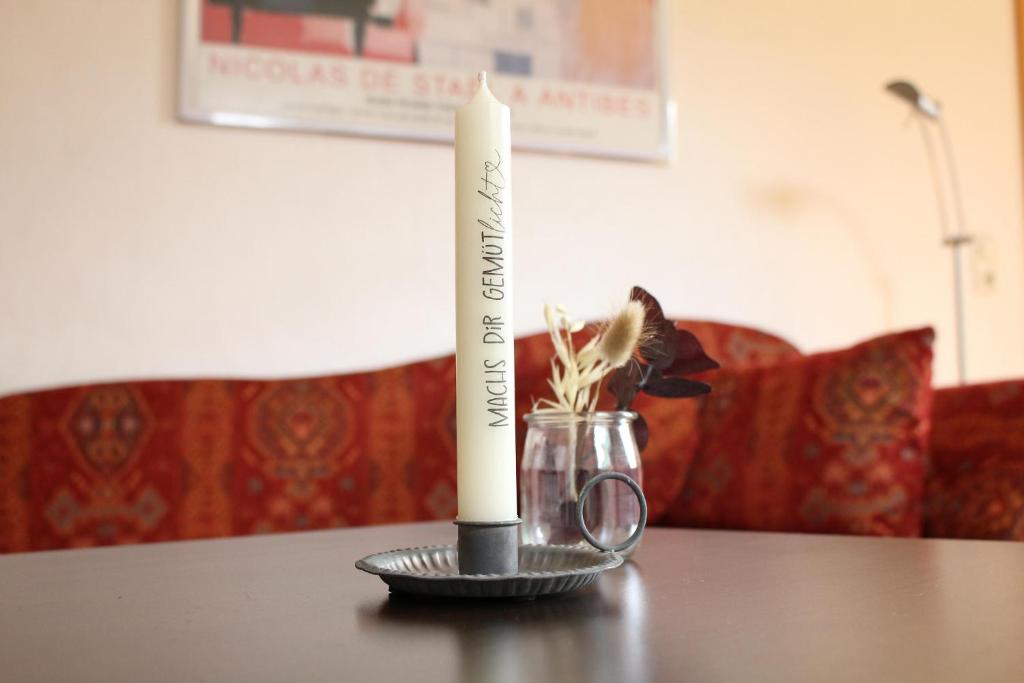 a candle on a table with a vase of flowers at Ferienwohnung Franziska in Hilders