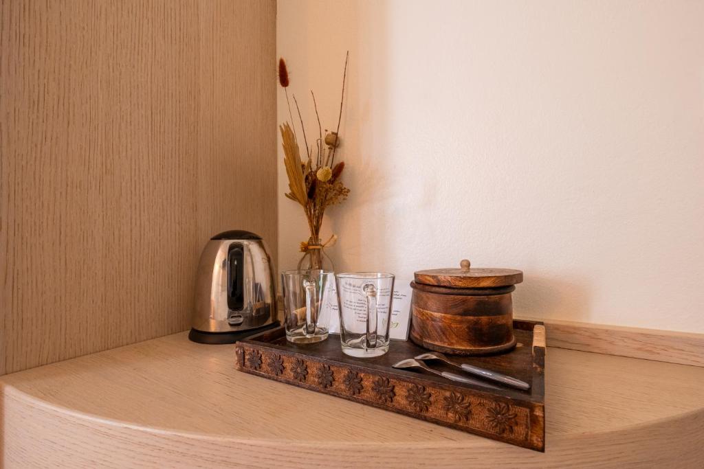 a wooden tray with glasses and a kettle on a table at Hôtel & Restaurant Les Mouettes in Belgodère