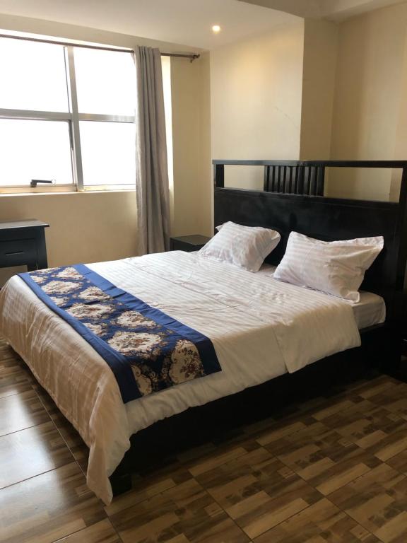 a bedroom with a large bed with a large window at Royal Hotel Apartments in Kampala