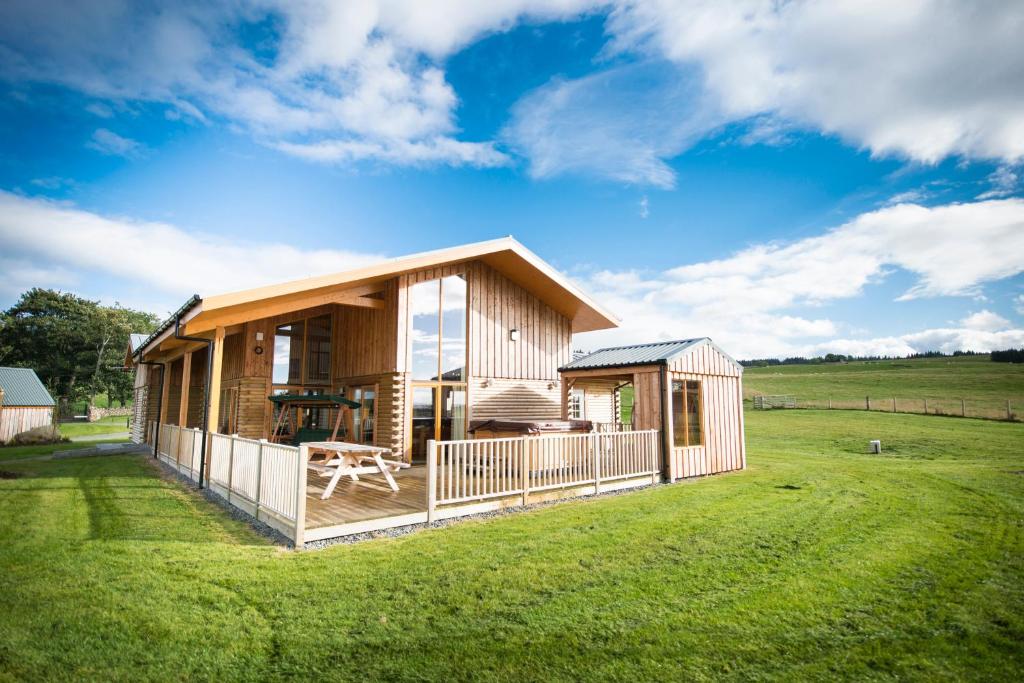 a house on a grassy field with a building at Aurae in Nairn