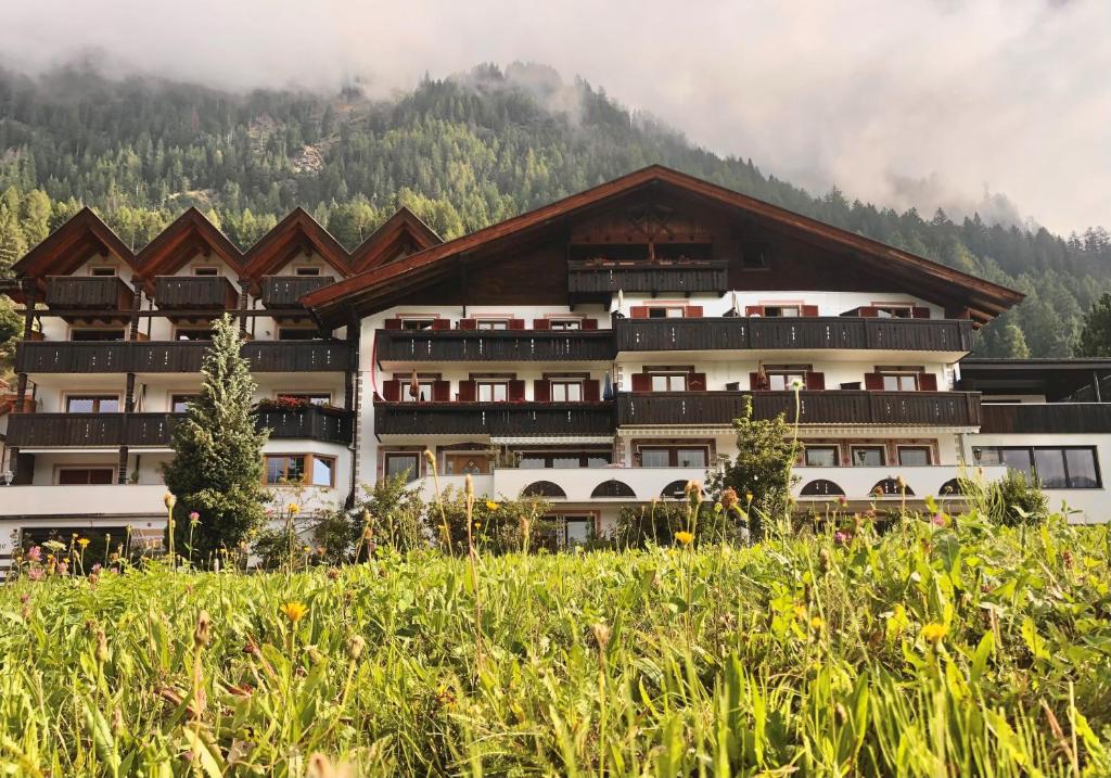 a large building with a mountain in the background at Hotel Alpenland in Moso