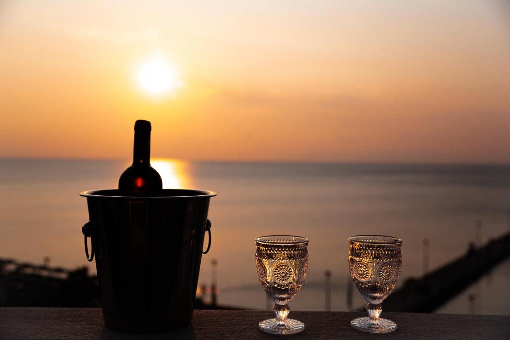 eine Flasche Wein in einer Tasse neben zwei Gläsern in der Unterkunft Luxury Plateia Rooms in Peraia