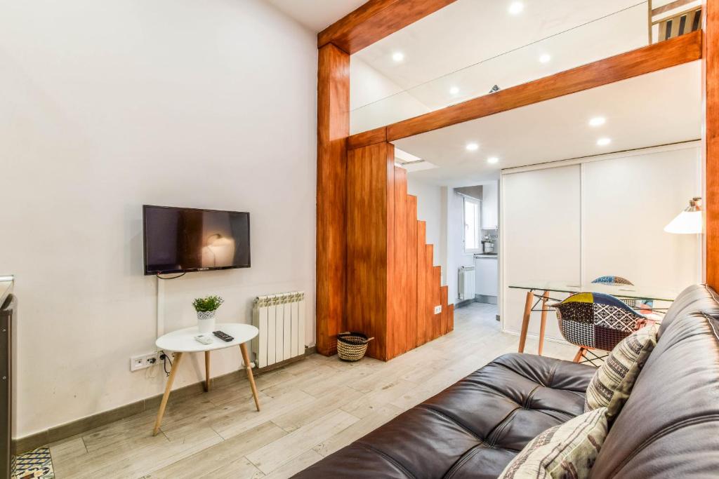 loft reformado en chueca para 4 personas في مدريد: غرفة معيشة مع أريكة وطاولة