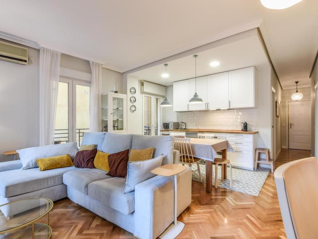 sala de estar con sofá azul y cocina en apartamento reformado-2 habitaciones-5 huespedes, en Madrid
