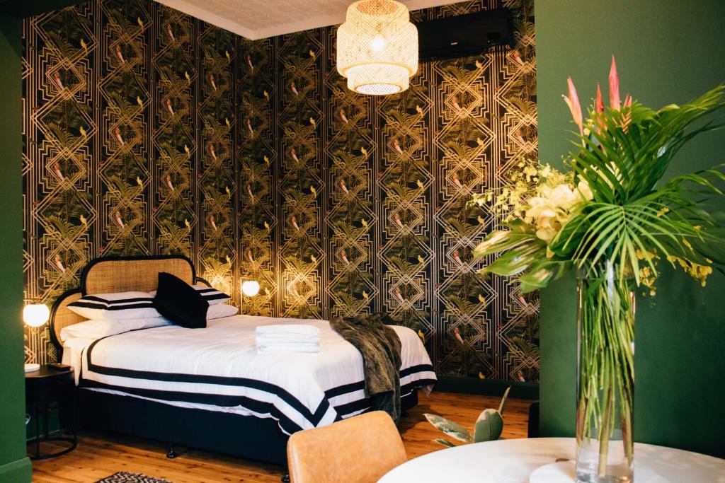 a bedroom with a bed and a green wall at Rooms of Renown - The Gilded Globe in Leeton