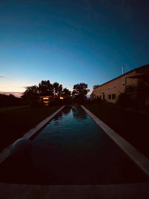 une petite piscine d'eau en face d'un bâtiment dans l'établissement Maison Drôles d'Oiseaux, à Plieux