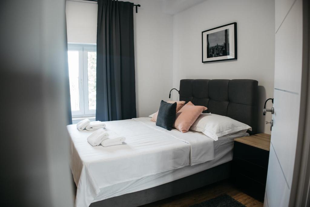 um quarto com uma cama com lençóis brancos e almofadas cor-de-rosa em Macao Apartmani em Vinkovci