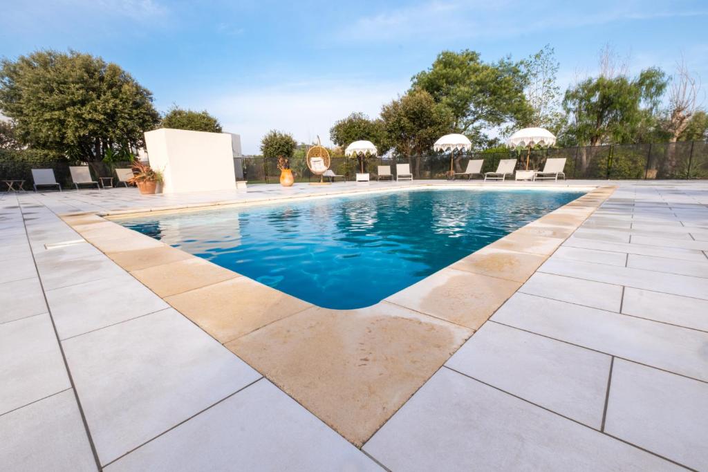 a swimming pool with blue water in a yard at Hôtel & Restaurant Les Mouettes in Belgodère