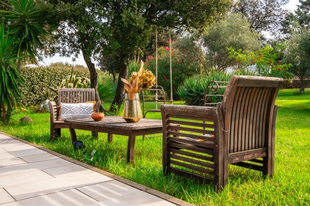 two chairs and a table in the grass at Hôtel & Restaurant Les Mouettes in Belgodère