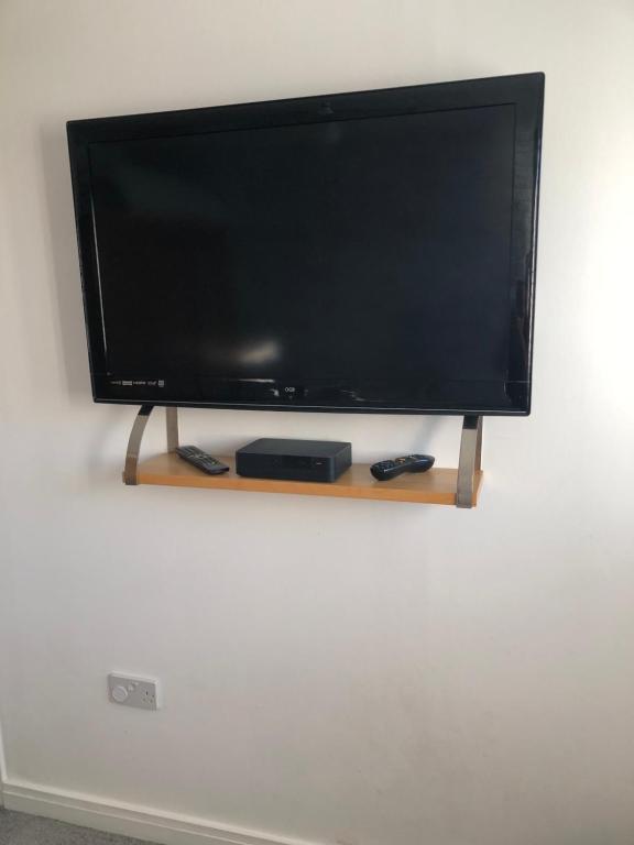 a flat screen tv sitting on a stand on a wall at Pats house in Earlswood