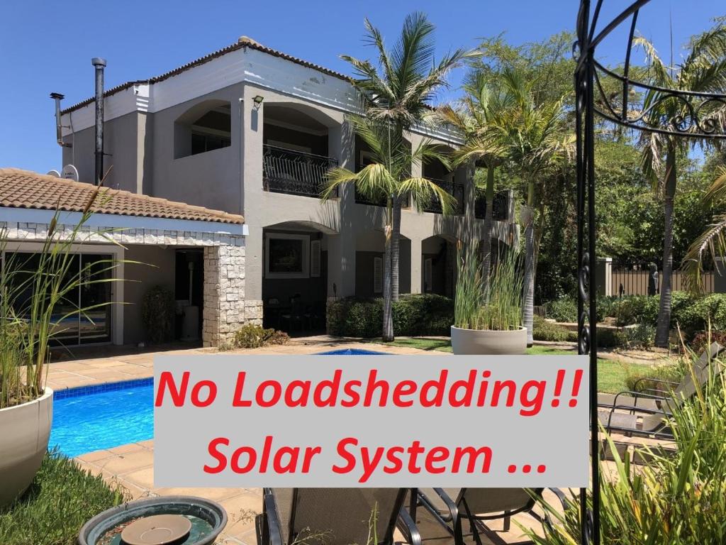 een huis met een bord dat leest dat geen leningen blokkeert zonnestelsel bij African Palm Cottage and Guesthouse in Durbanville