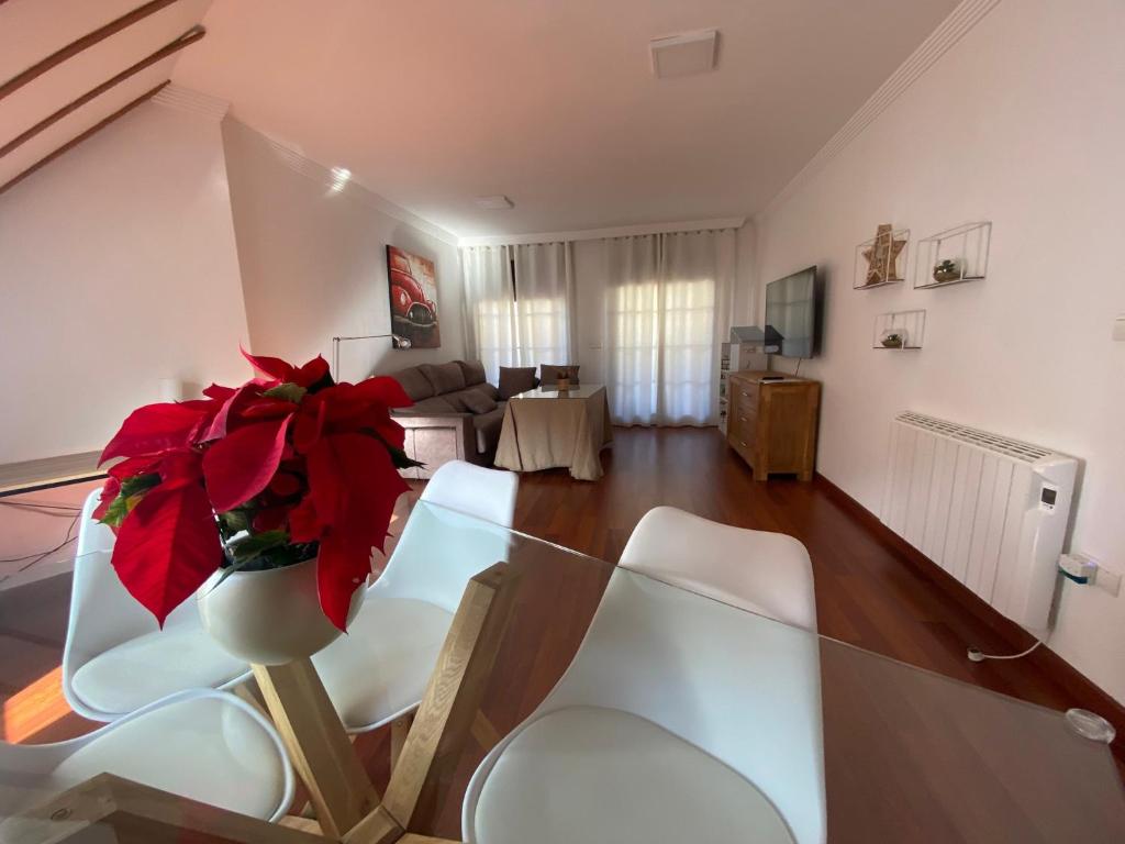 un soggiorno con tavolo in vetro e vaso con fiori rossi di Increible Ático centro Monachil a Monachil
