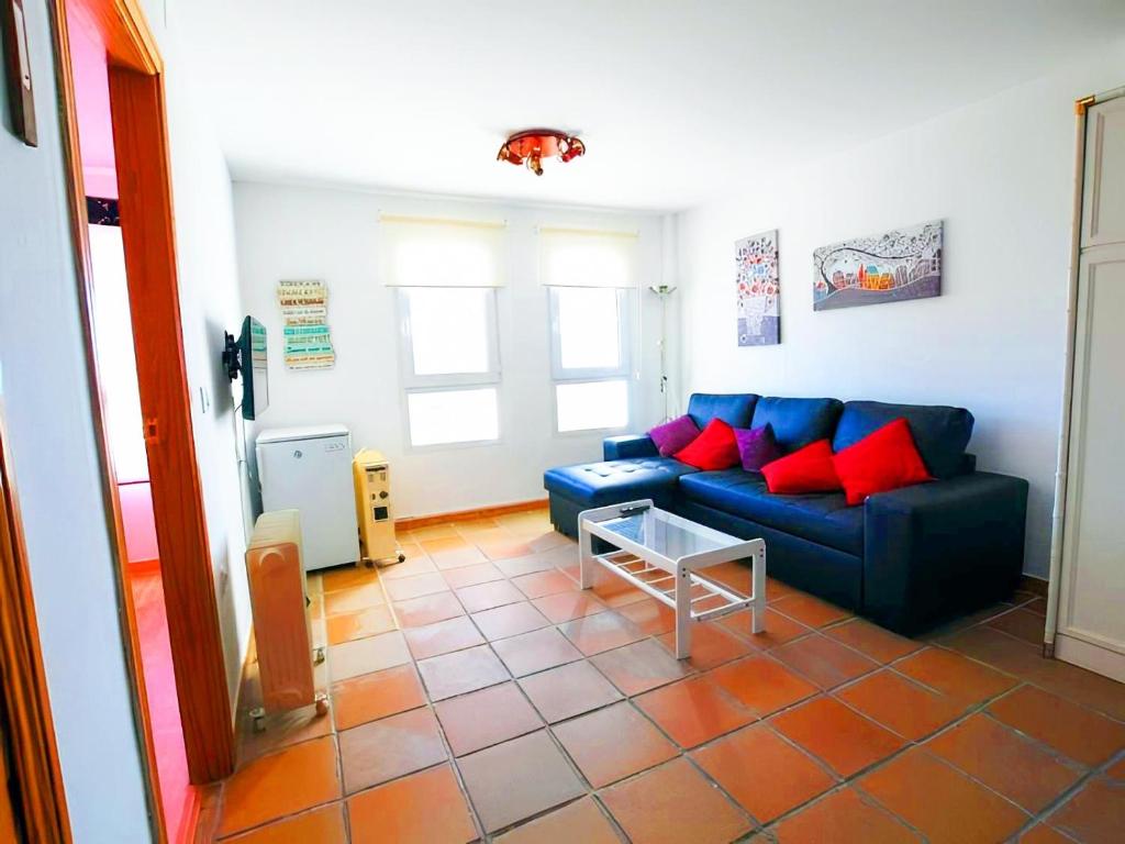 a living room with a blue couch and red pillows at Apartamento con Parking Cubierto Zona Alta in Sierra Nevada