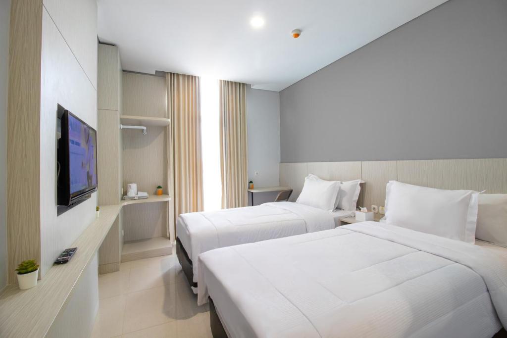 a hotel room with two beds and a flat screen tv at MIC Residence in Kejayan