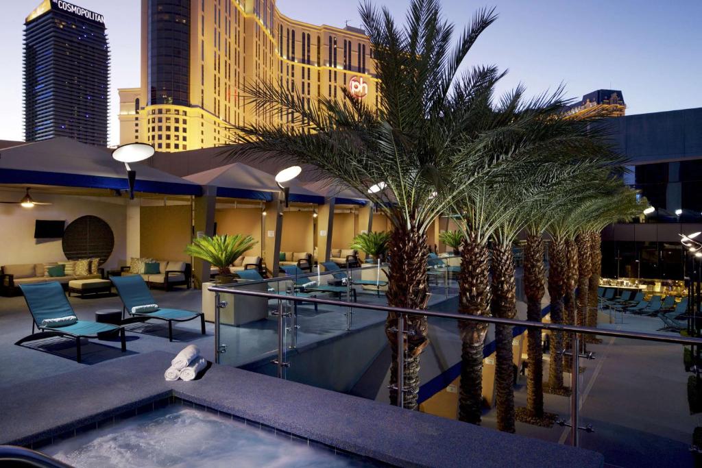 a hotel with palm trees and chairs and a pool at Hilton Club Elara Las Vegas in Las Vegas