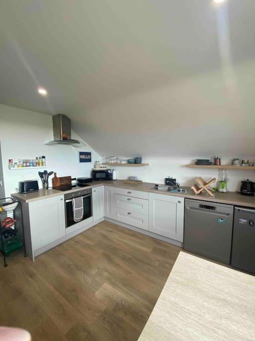 a large kitchen with white cabinets and wooden floors at Island View Apartment in Droíchead an Chláir