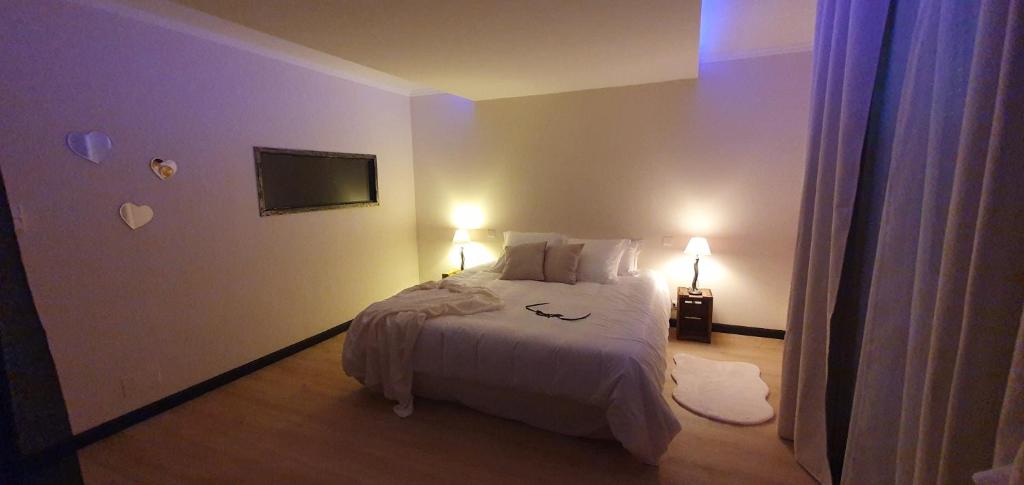 een slaapkamer met een wit bed en 2 lampen bij La Vallée Douce 