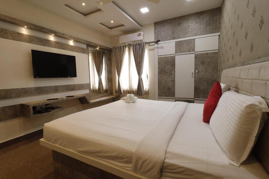 SR BOUTIQUE STAY SERVICE APARTMENT في كويمباتور: غرفة نوم بسرير ابيض كبير وتلفزيون بشاشة مسطحة