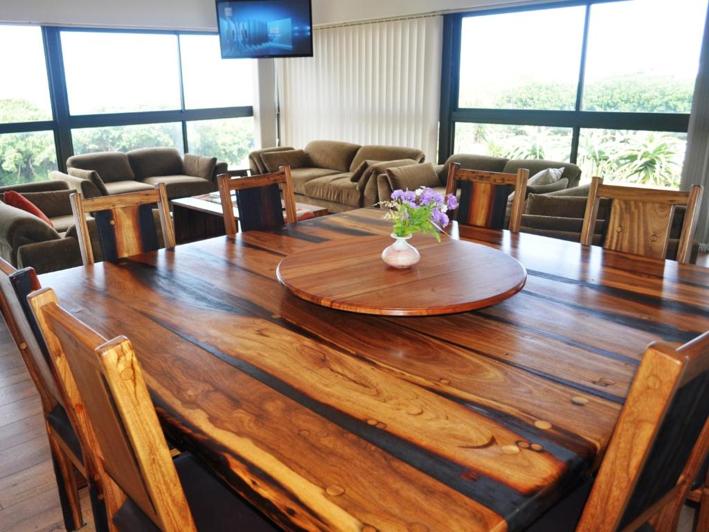 a wooden table with a vase of flowers on top at Great White Accommodation in Kleinbaai
