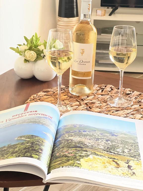un livre ouvert sur une table avec des verres de vin dans l'établissement Appartement entre village et plages., à Saint-Cyr-sur-Mer