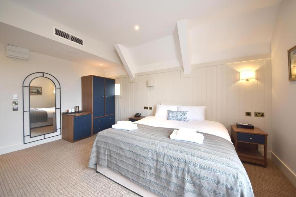 1 dormitorio con 1 cama grande y espejo en The Elvetham Hotel, en Farnborough