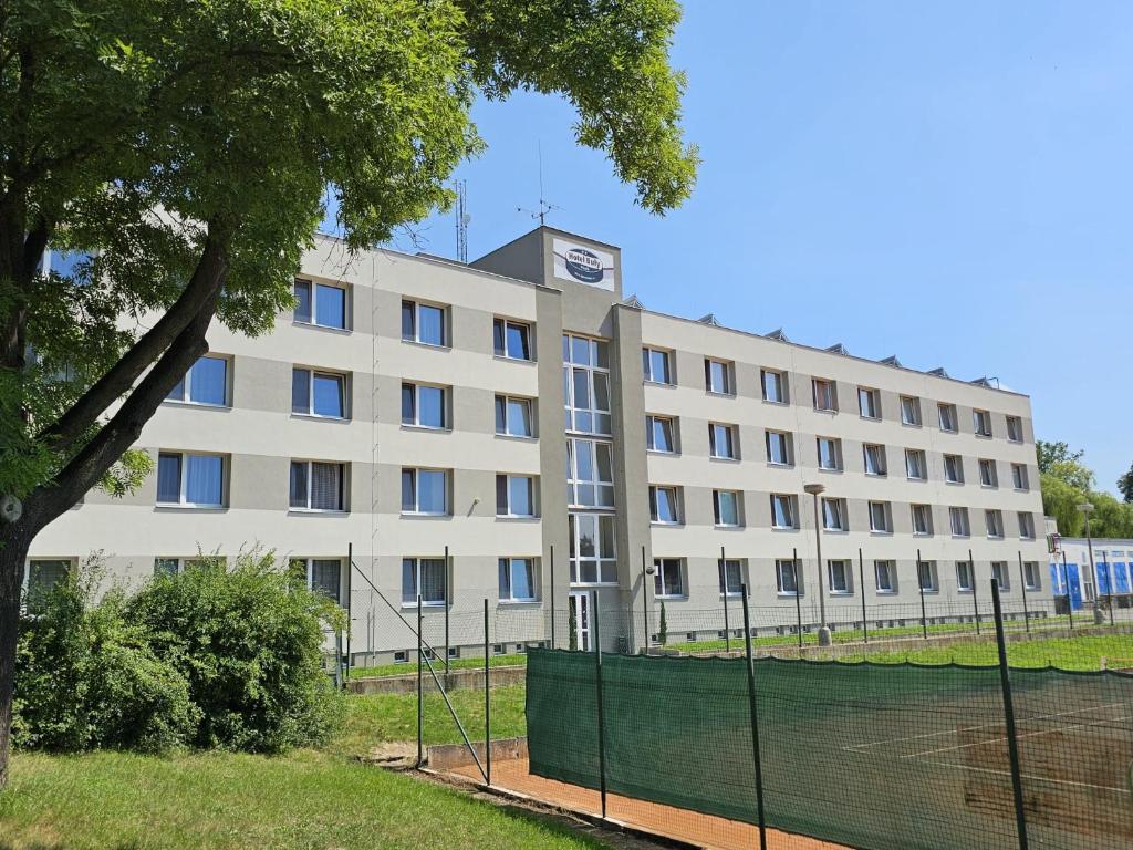 een gebouw met een tennisbaan voor een hek bij Hotel Buly in Písek