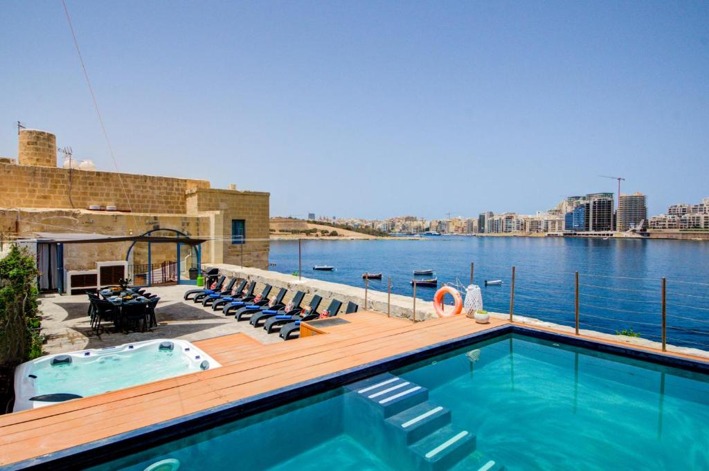 a swimming pool with a deck next to the water at Valletta Waterfront Villa with Pool and Jacuzzi in Valletta