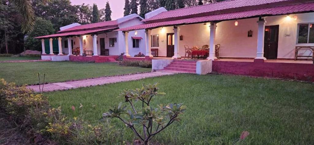 a white house with a grass yard and a house at KP Cottages in Kānker