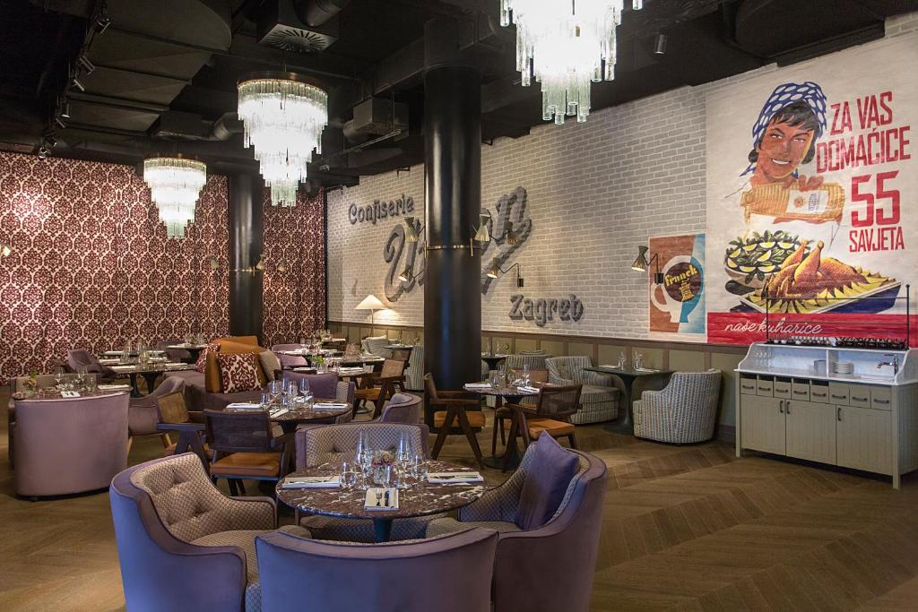 Dining room with crystal chandelier, 'Conjacle' wall sign, Zagreb mural, purple banquettes and self-serve cold display at Canopy by Hilton Zagreb City Centre in Zagreb