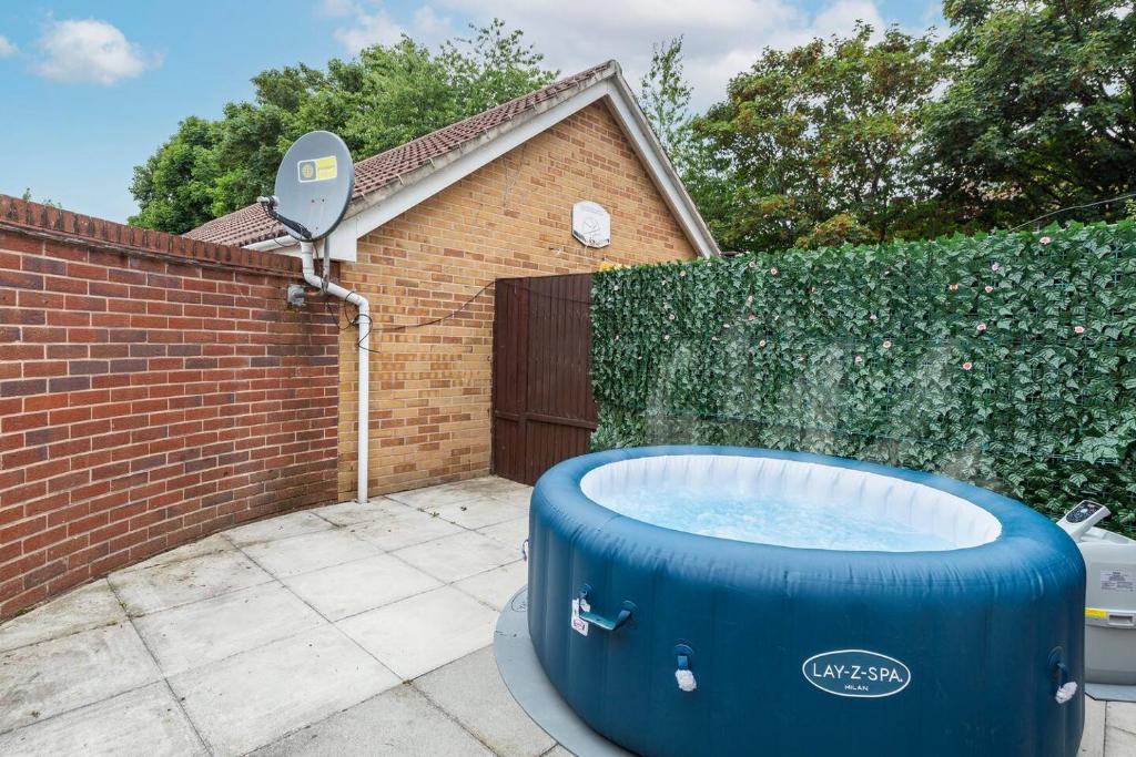 una bañera azul en un patio junto a una valla de ladrillo en Sleek Stylish House 2 Parking - Hot tub & Arcade, en Bristol