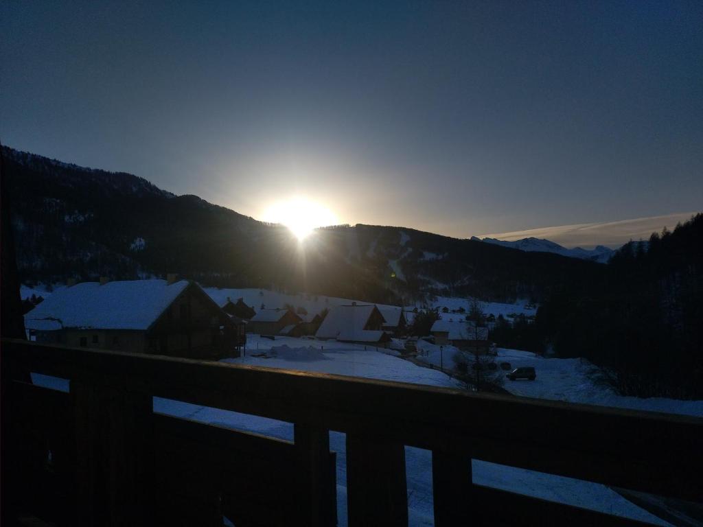a sun setting over a town with snow covered mountains at Les Balcons de L'Izoard - L'écureuil in Arvieux