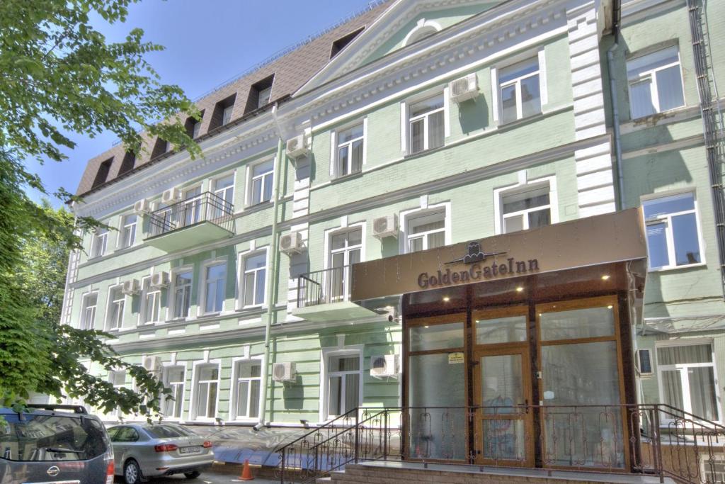 un edificio verde e bianco con un'auto parcheggiata di fronte di Golden Gate Inn a Kiev