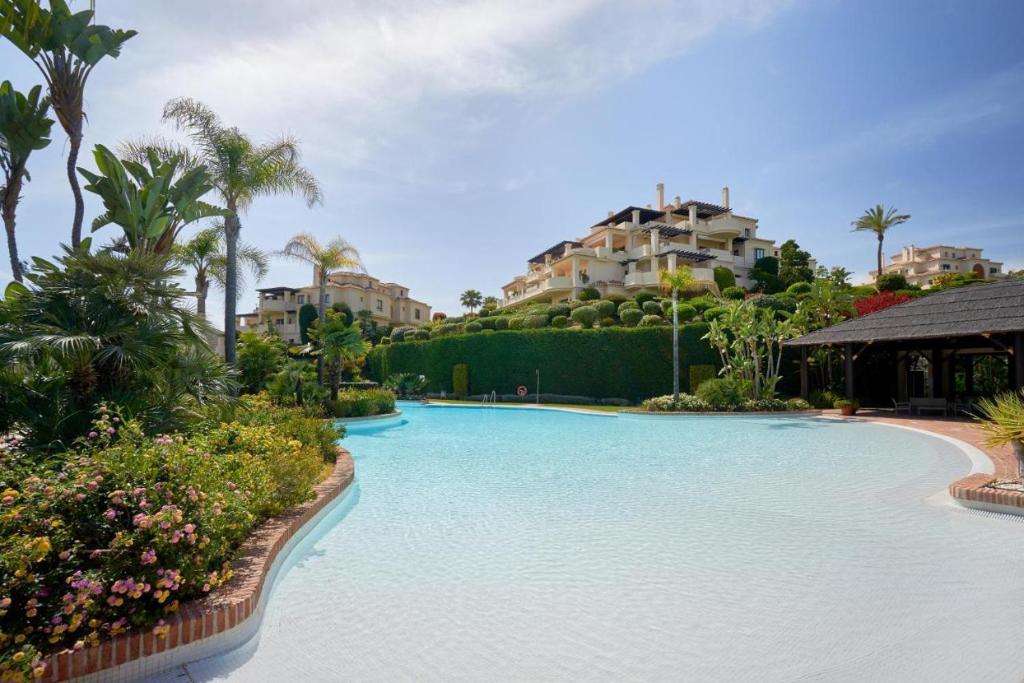 a pool at a resort with palm trees and buildings at Capanes de Golf Luxury Apt in Benahavís