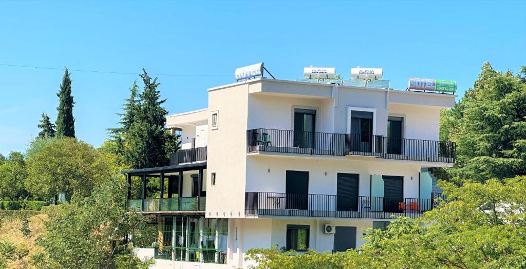 a white building with balconies and trees at Hotel Trifoni in Përmet