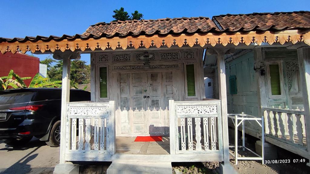 ein altes Haus mit einem Tor und einem geparkten Auto in der Unterkunft Omah Kayu Palagan in Ngaglik