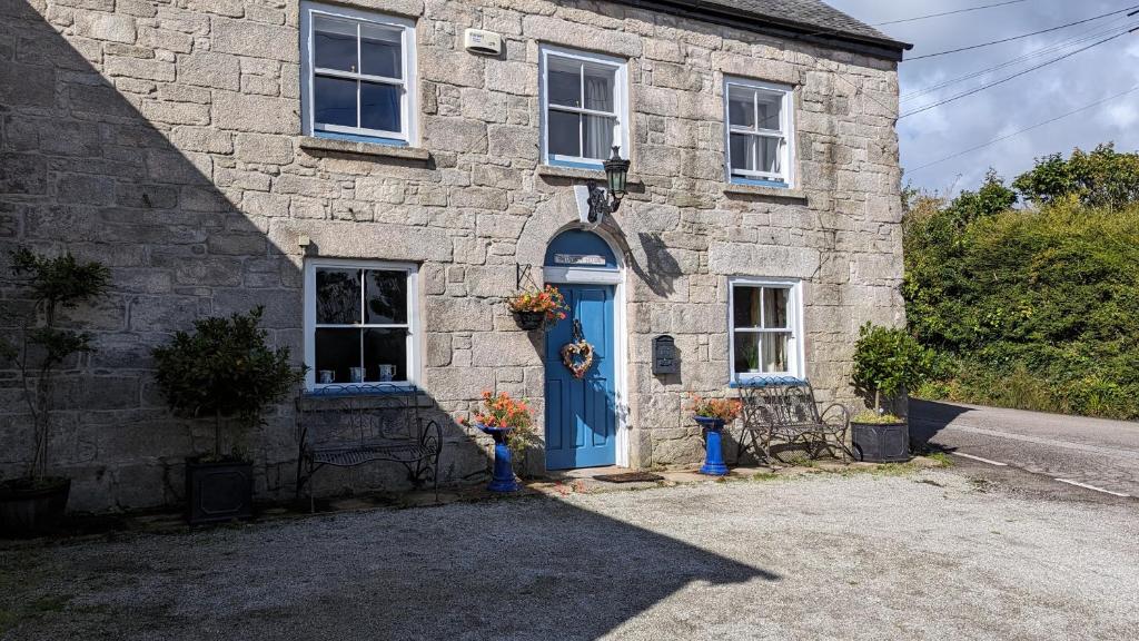 uma casa de pedra com uma porta azul e um quintal em Britannia House Vintage B&B Cornwall em Helston