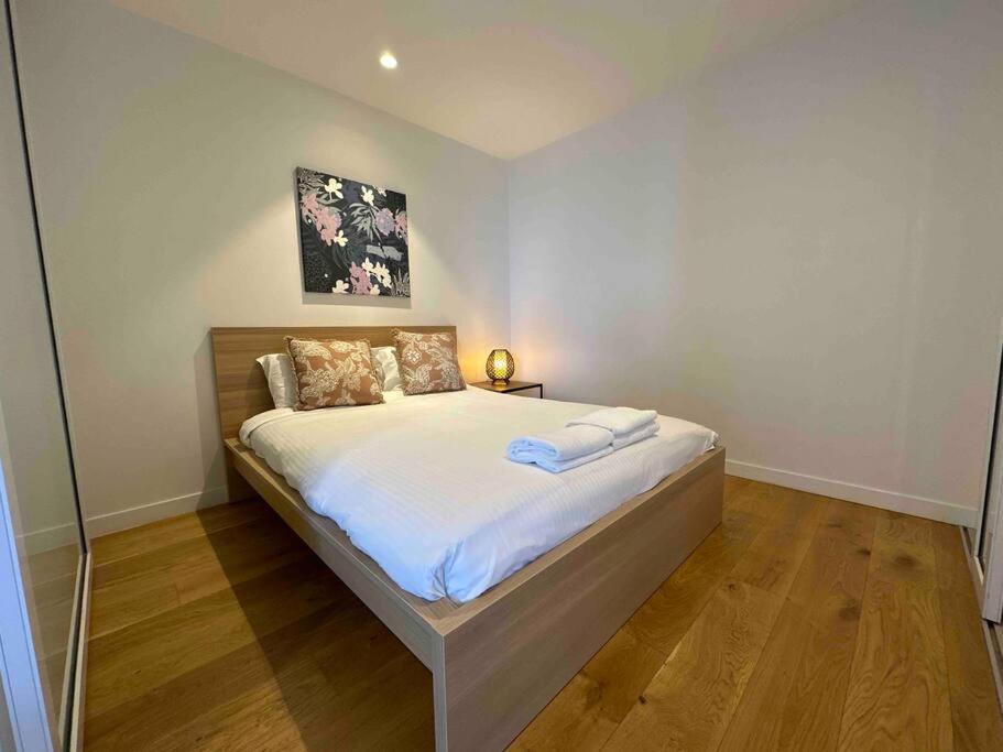 a bedroom with a large bed with white sheets at Nest Apartments on Rose Lane in Melbourne