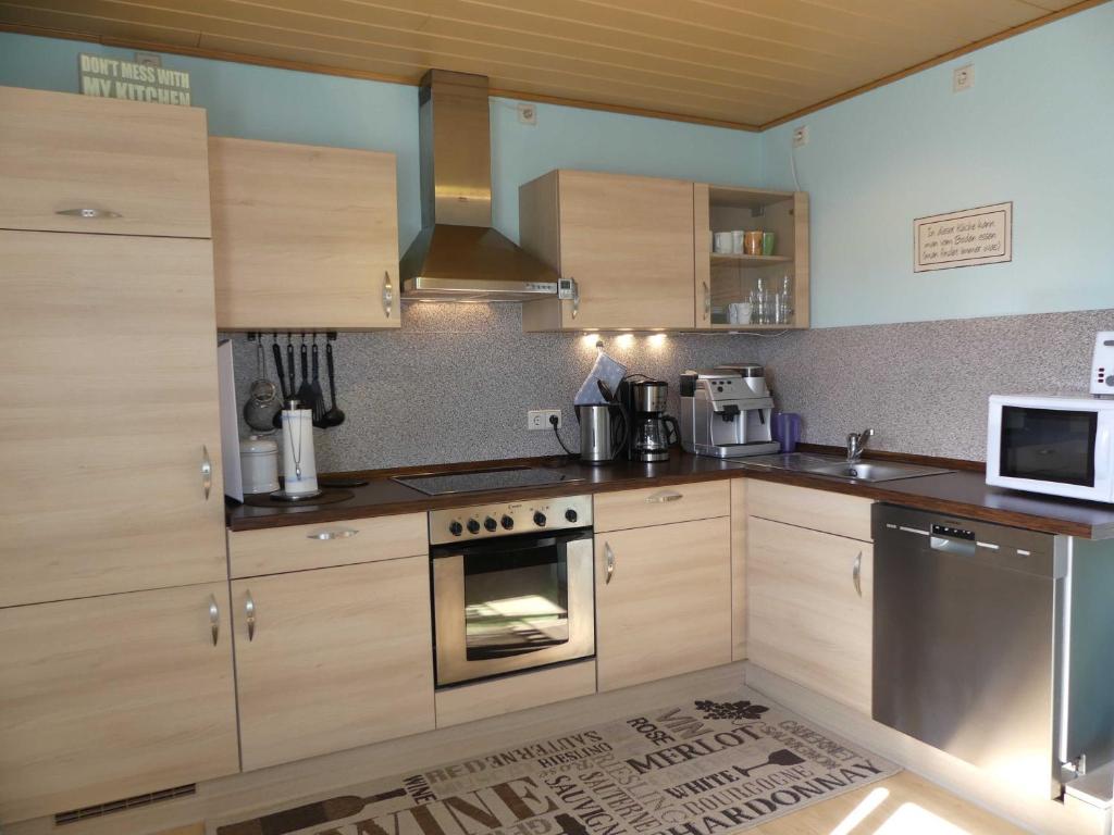 La cuisine est équipée de placards en bois et d'un four avec plaques de cuisson. dans l'établissement Ferienwohnung Schanbacher, à Beerfelden