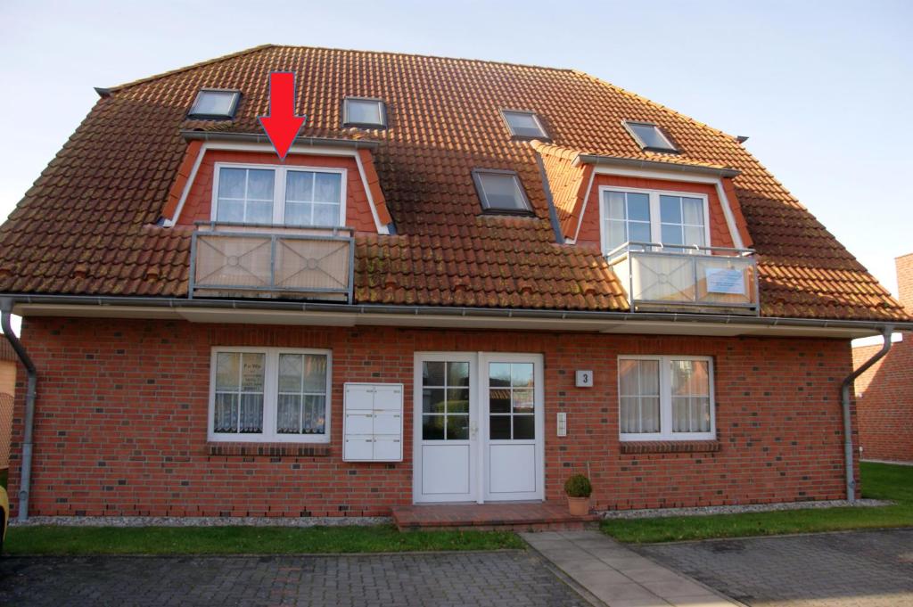 une maison en briques avec une flèche rouge dans l'établissement Seeräuber, à Schönberger Strand