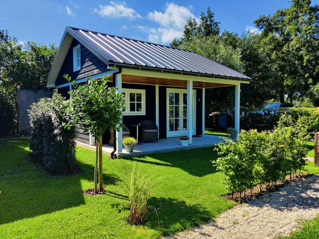 a tiny house in a yard with a garden at Park De Driesprong in Nieuwveen