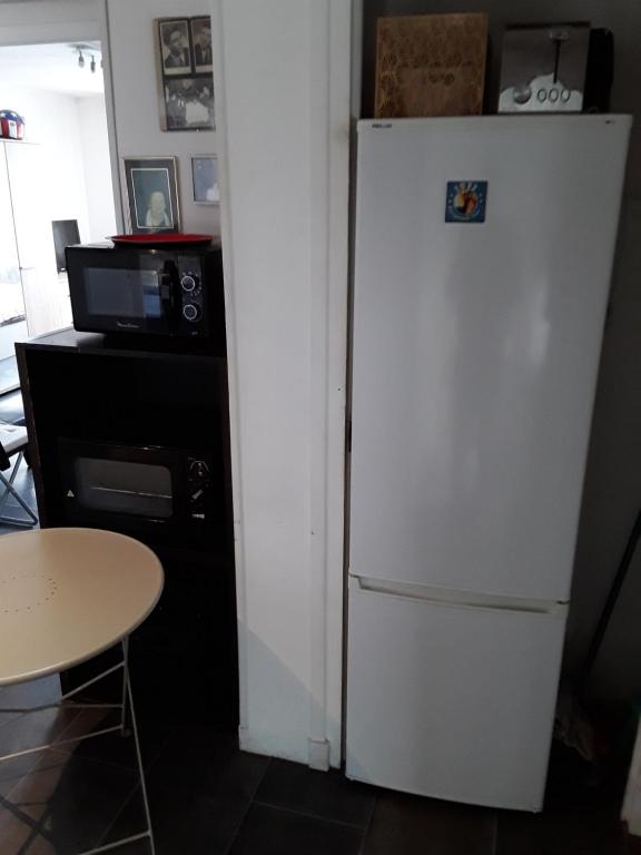 a white refrigerator in a kitchen with a table at Maison 48m2 deux chambres cour privé et personnelle pour motos ou voitures 4 Pers proche mairie et bus tram in Le Pont-de-Claix