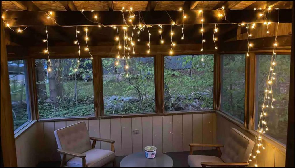 a porch with a table and chairs and lights at Oceans - KING BED Cabin Loft & Fireplace in Tobyhanna