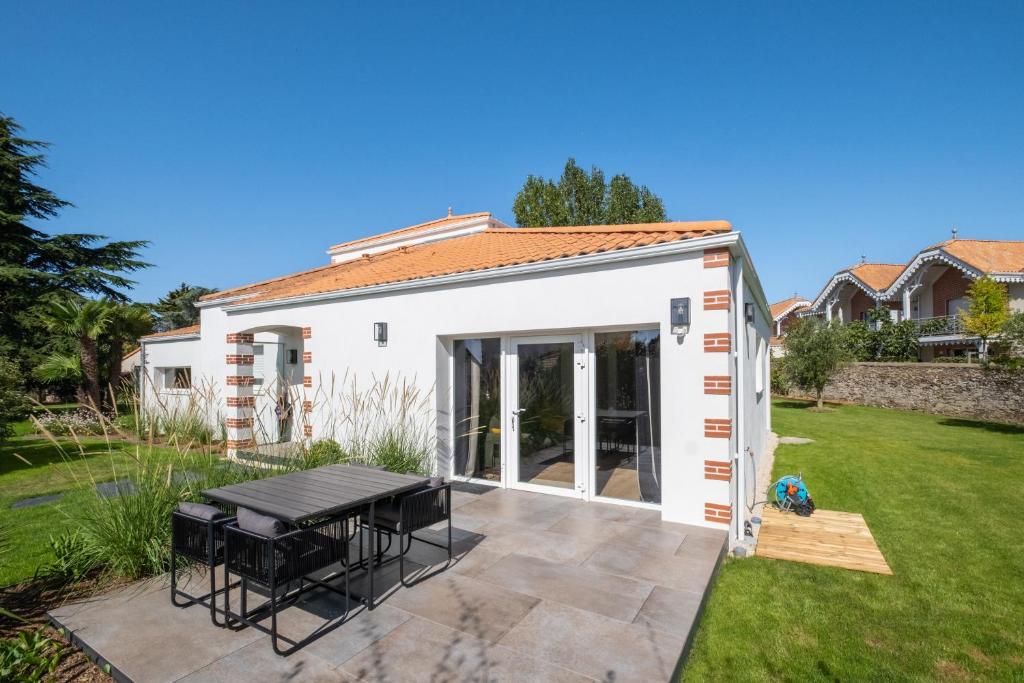 a small white shed with a picnic table in a yard at Le Clos de Jade - Appt 3 étoiles avec piscine partagée in Pornic