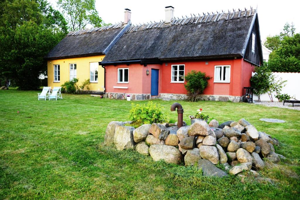 a red and yellow house with a rock wall in front of it at Onkel Enkels Pensionat in Tomelilla