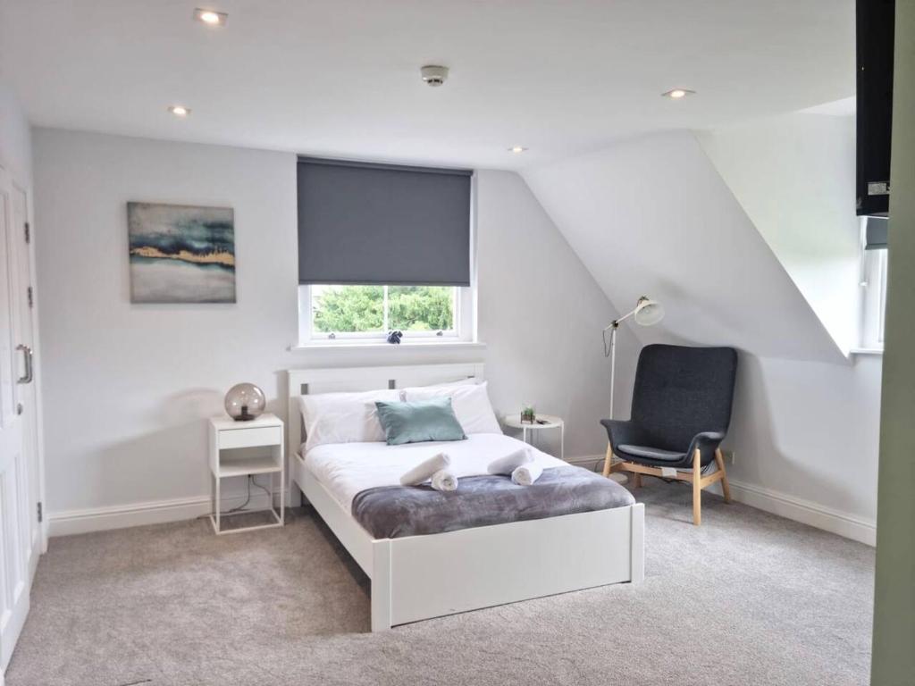 a white bedroom with a bed and a chair at Hyland Apartment by CityNest in Chelmsford