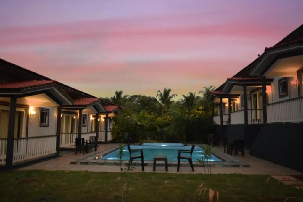 戈阿韦尔哈FabEscape Vagator Retreat Resort With Swimming Pool - Nr Vagator Beach的别墅前方设有游泳池和桌子