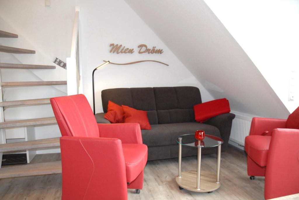 a living room with a couch and red chairs at Mien Dröm in Norddeich